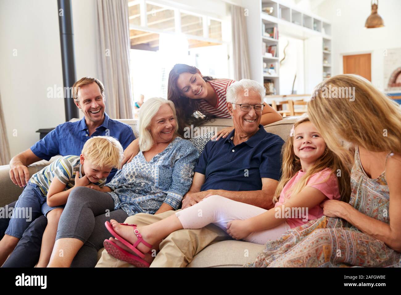 Multi-Generation Family Sitting On Sofa At Home Relaxing And Chatting Stock Photo