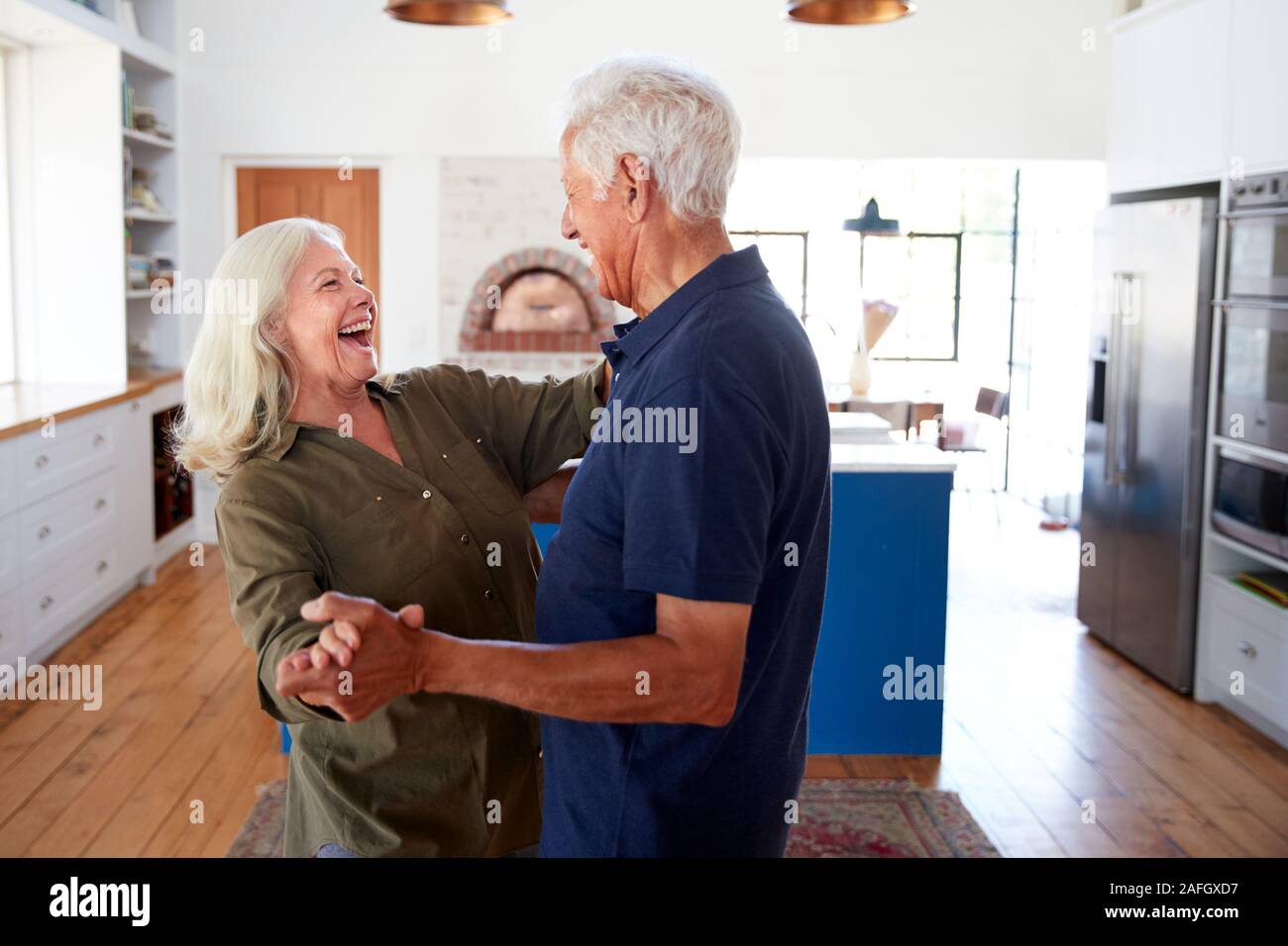 Senior Couple At Home Dancing In Kitchen Together Stock Photo