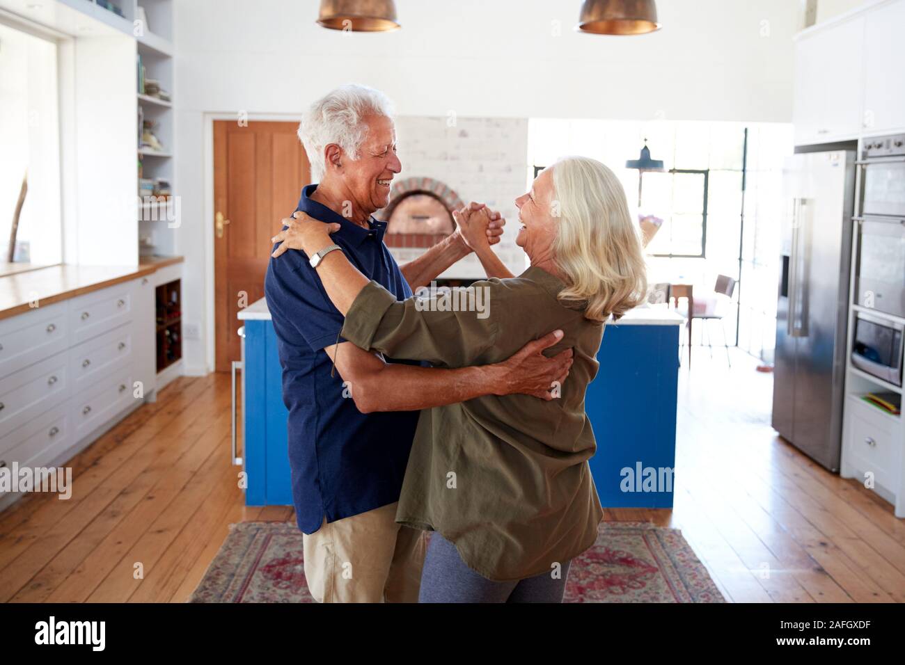 Senior Couple At Home Dancing In Kitchen Together Stock Photo
