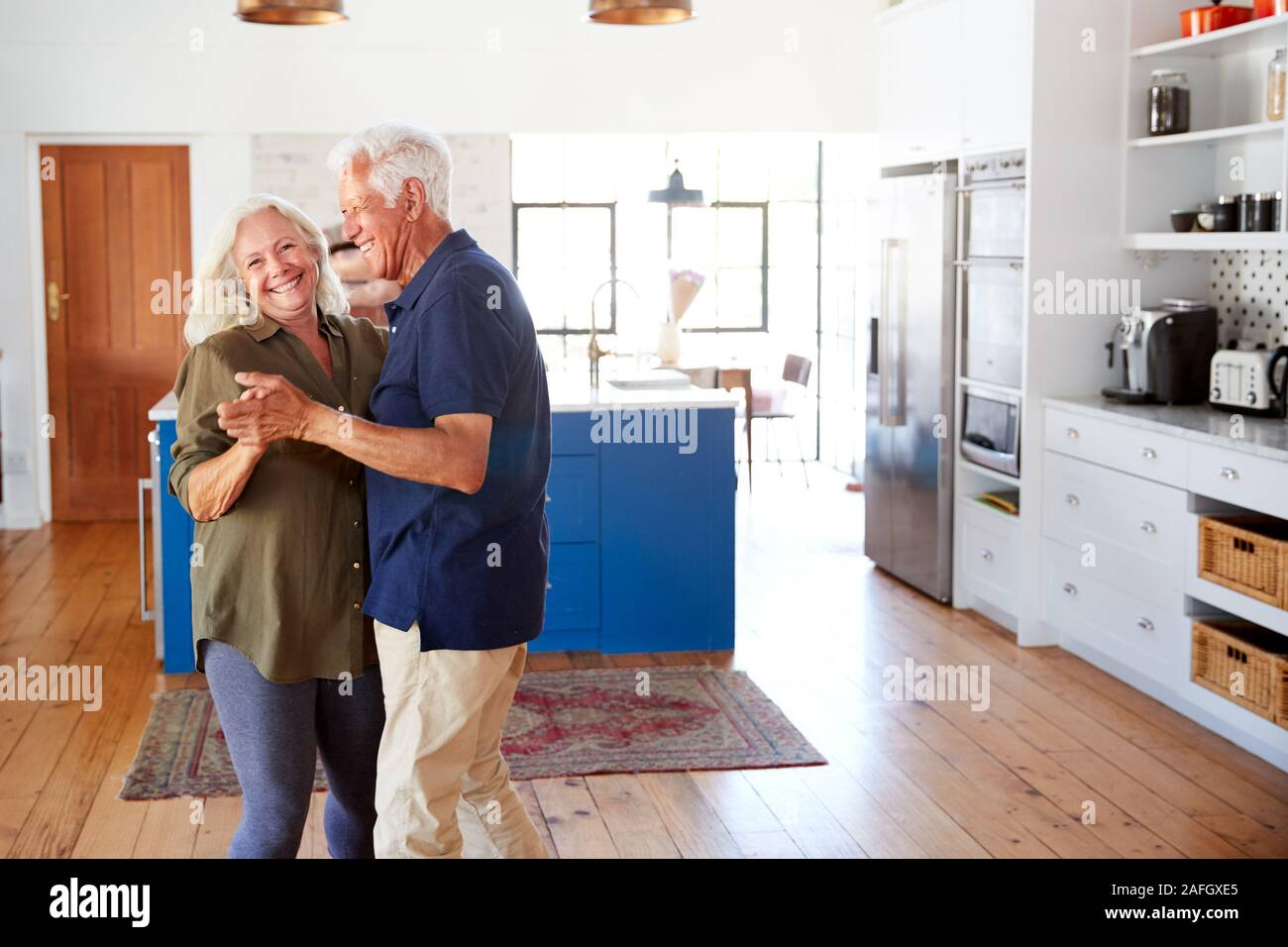 Senior Couple At Home Dancing In Kitchen Together Stock Photo