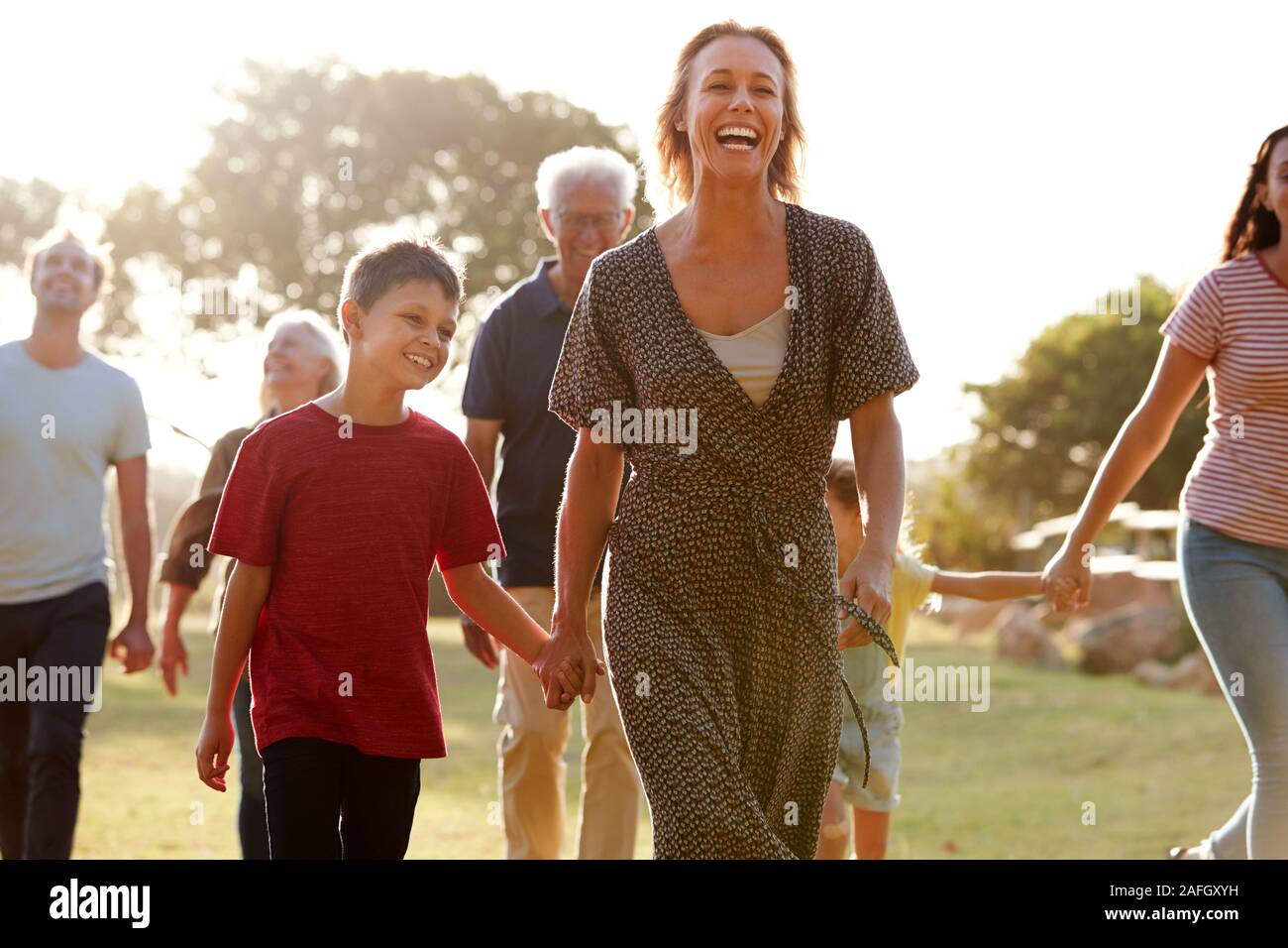 Multi-Generation Family Walking In Countryside Against Flaring Sun Stock Photo