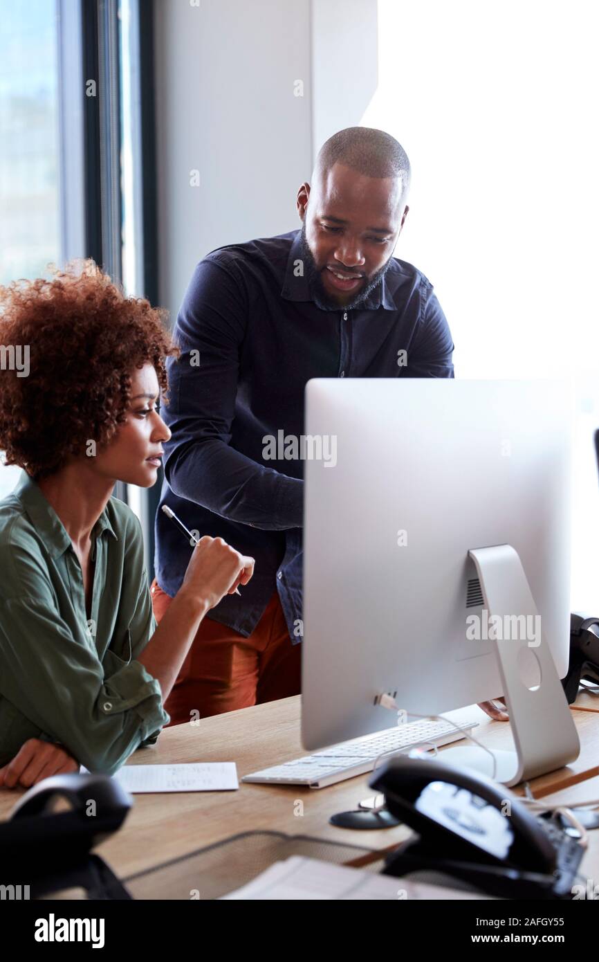 Young creative professionals working together at a computer in an office, vertical, close up Stock Photo