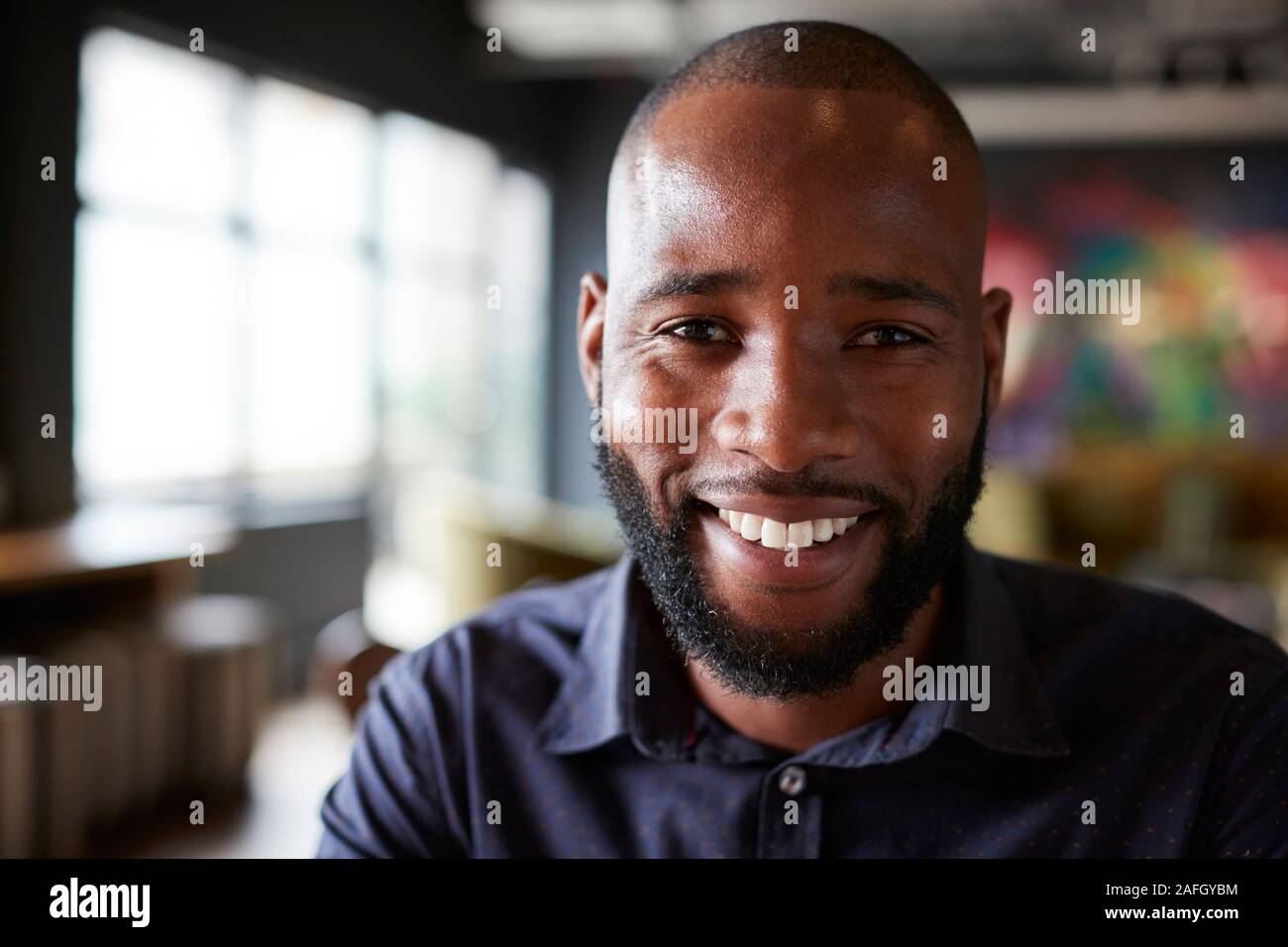 Mid adult black male creative sitting in an office dining area, head and shoulders close up Stock Photo