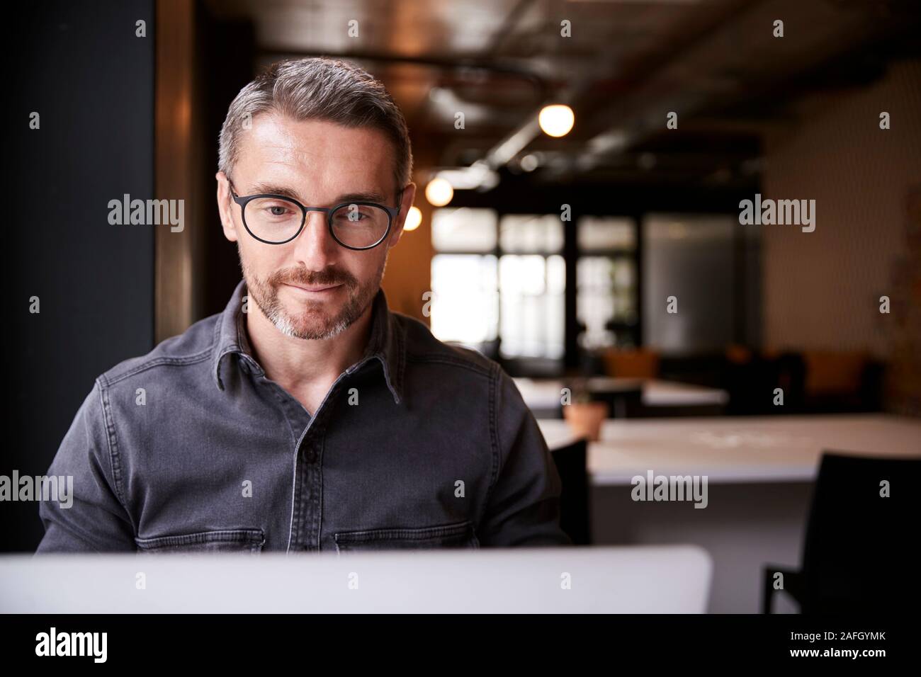 Middle aged white male creative sitting in an office looking at laptop computer screen, close up Stock Photo