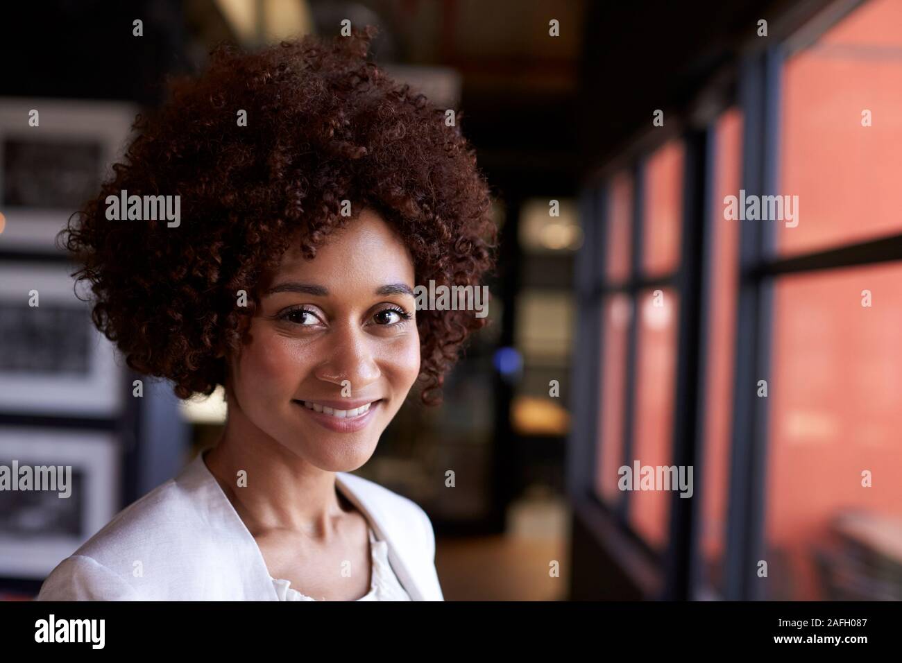 Millennial black businesswoman smiling to camera by the window in an office, close up Stock Photo