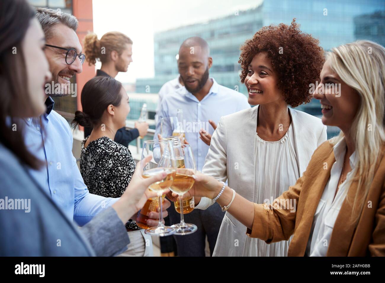 Socialising office colleagues raising glasses and making a toast with