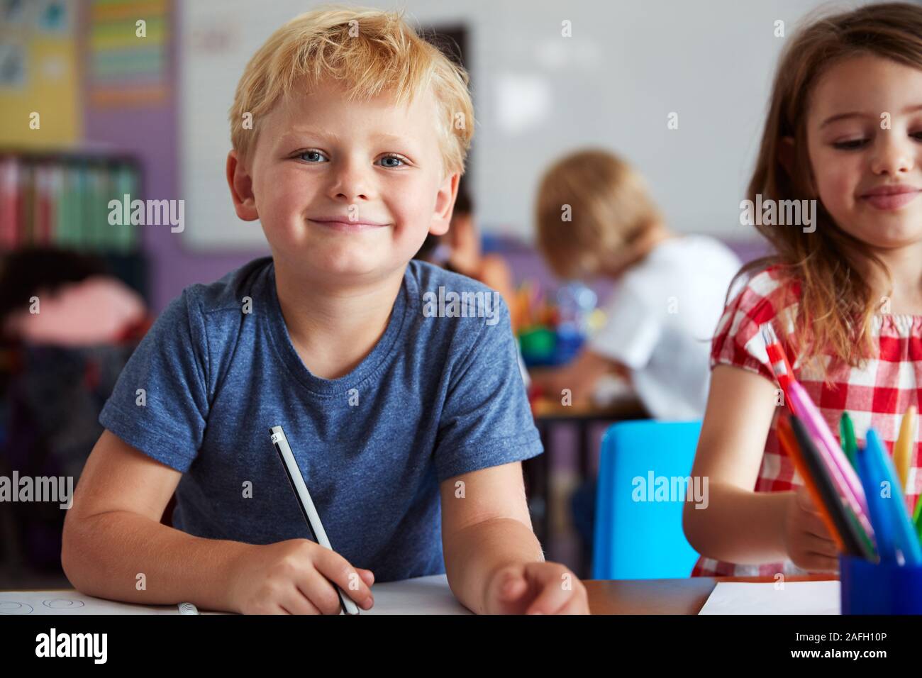 Portrait Of Male And Female Elementary School Pupils Working At Desk Stock Photo