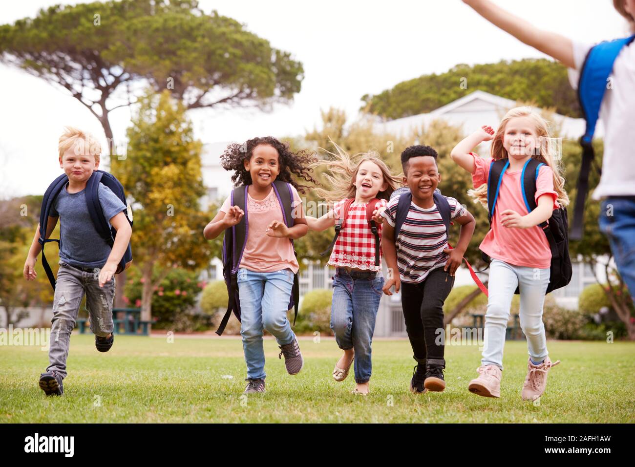 Excited Elementary School Pupils Running Across Field At Break Time Stock Photo