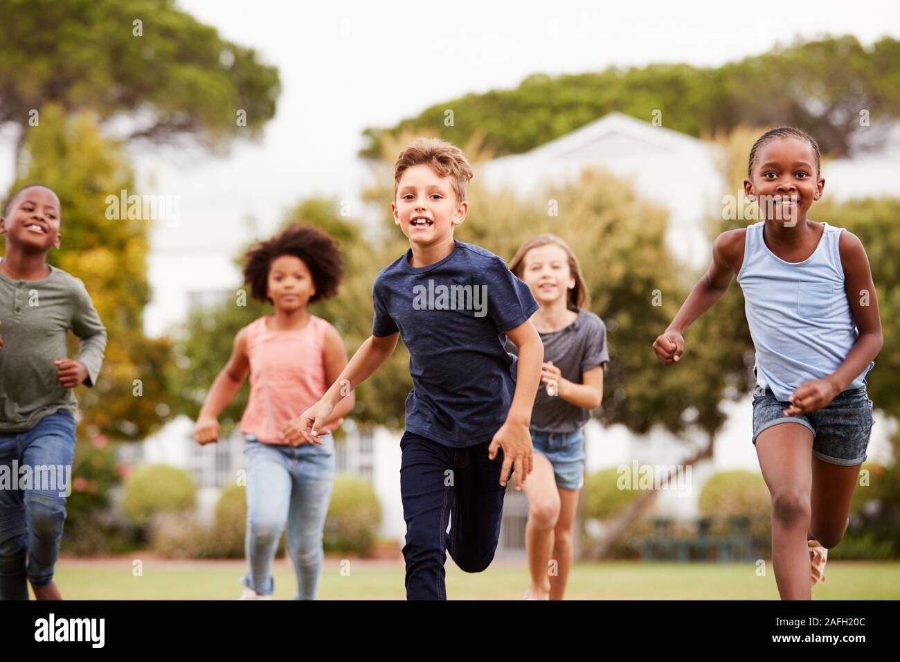 Excited Elementary School Pupils Running Across Field At Break Time Stock Photo