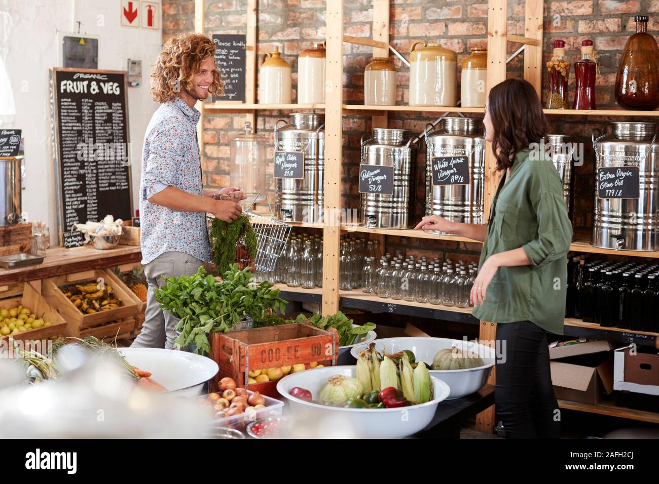 Couple Buying Fresh Fruit And Vegetables In Sustainable Plastic Free Grocery Store Stock Photo