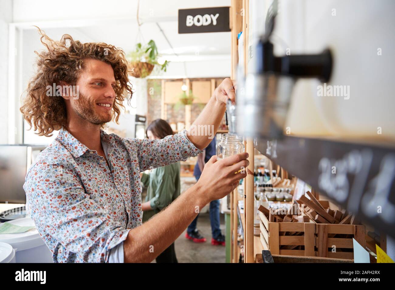 Man Filling Container With Dishwasher Powder In Plastic Free Grocery Store Stock Photo