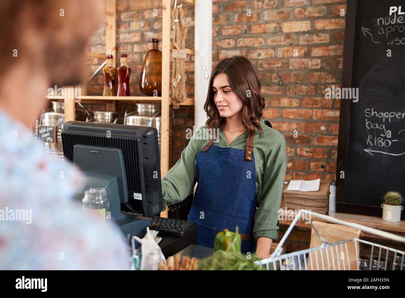 Customer Paying For Shopping At Checkout Of Sustainable Plastic Free Grocery Store Stock Photo