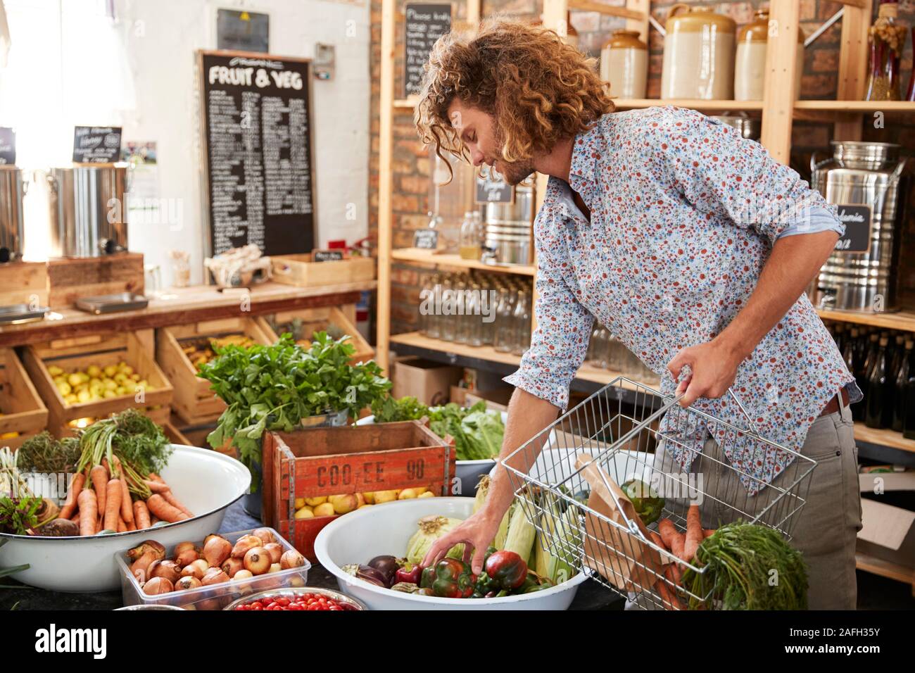 Man Buying Fresh Fruit And Vegetables In Sustainable Plastic Free Grocery Store Stock Photo