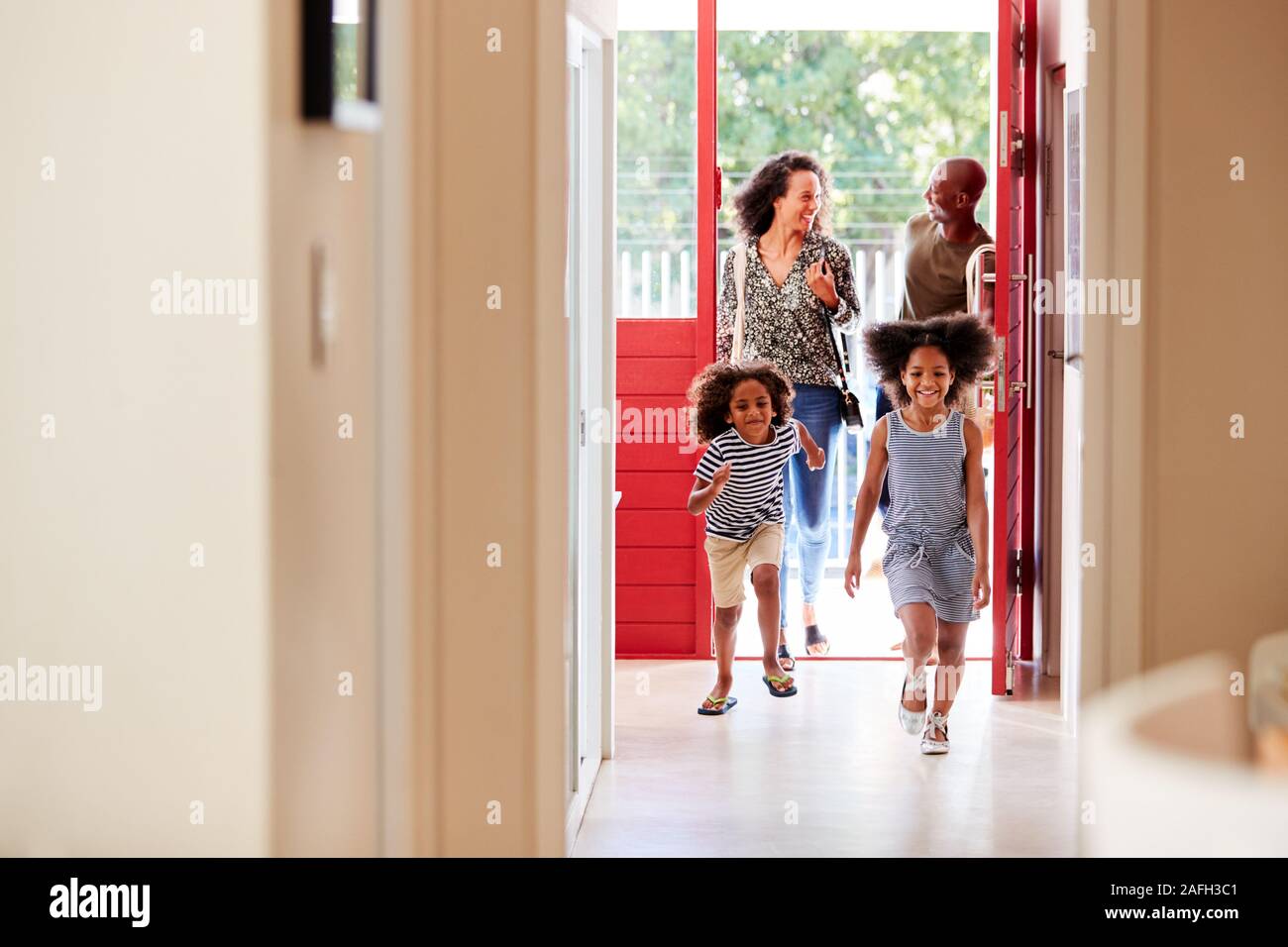 Family Returning Home From Shopping Trip Using Plastic Free Grocery Bags Opening Front Door Stock Photo