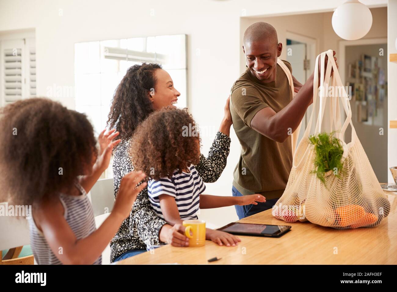 Family Returning Home From Shopping Trip Unpacking Plastic Free Grocery Bags Stock Photo