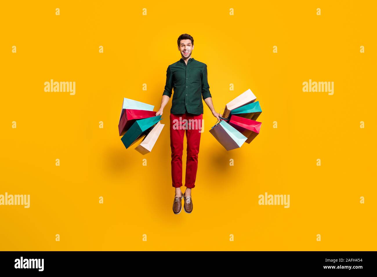 Full length photo of amazed funky crazy guy jump hear wonderful sales  scream wow go shop buy purchase hold many bags wear stylish green shirt red  Stock Photo - Alamy