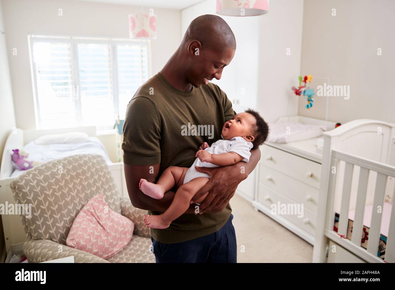 Proud Father Cuddling Baby Son In Nursery At Home Stock Photo