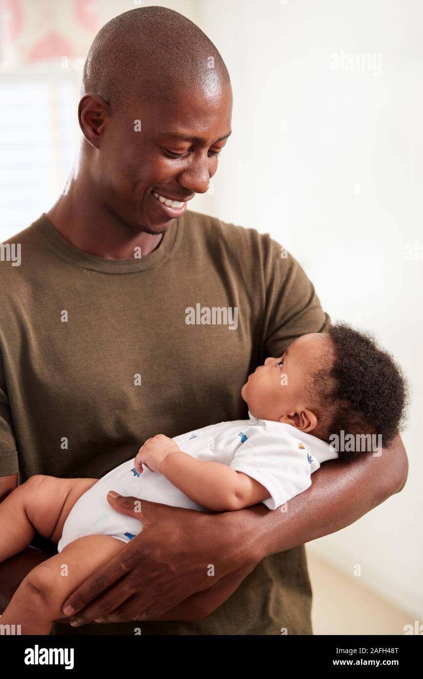 Proud Father Cuddling Baby Son In Nursery At Home Stock Photo