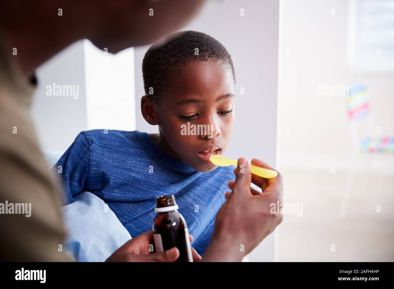 Father Giving Sick Son Ill In Bed Medicine From Bottle Stock Photo