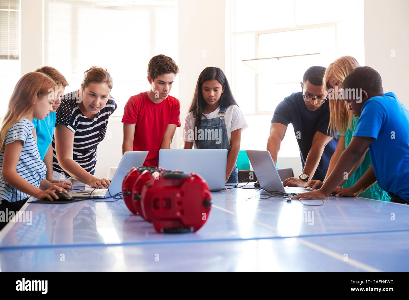 Group Of Students In After School Computer Coding Class Learning To Program Robot Vehicle Stock Photo