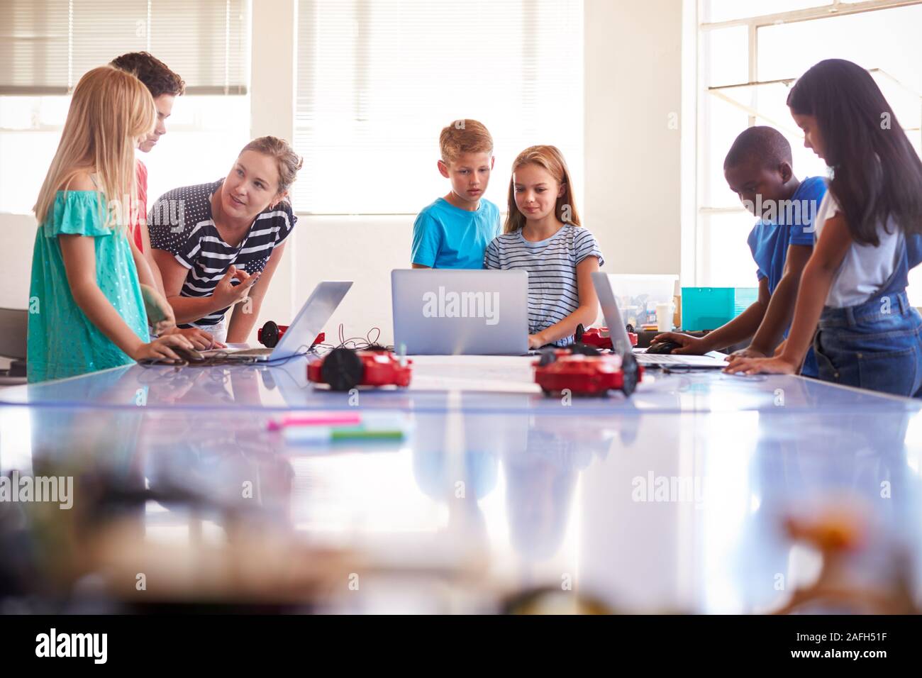 Group Of Students In After School Computer Coding Class Learning To Program Robot Vehicle Stock Photo