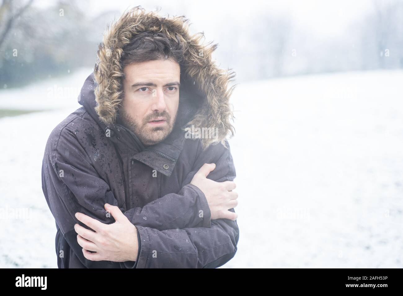 Man wearing warm clothes freezing in the snow Stock Photo