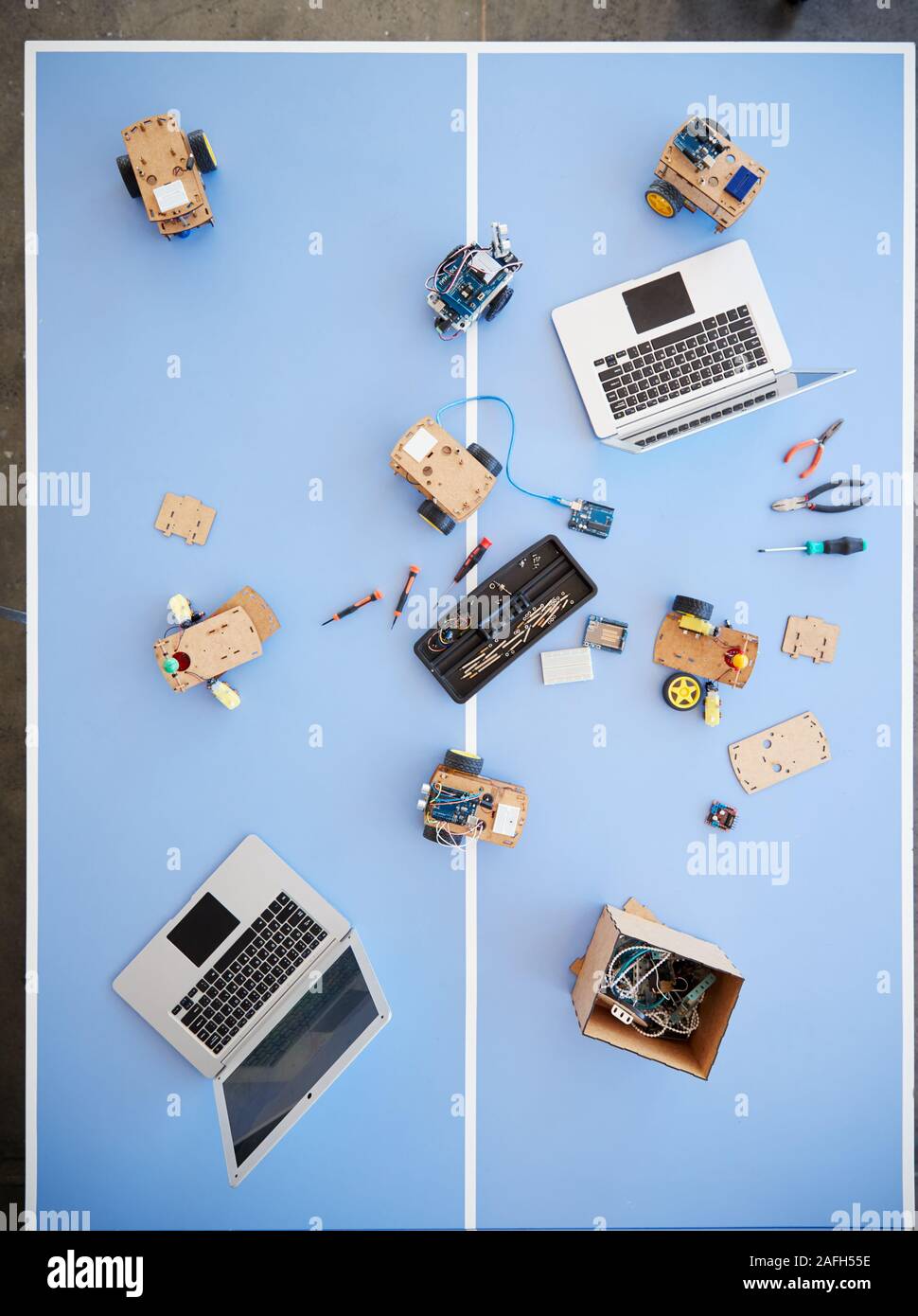 Overhead View Of Laptops And Robotic Vehicles On Table In School Computer Coding Class Stock Photo