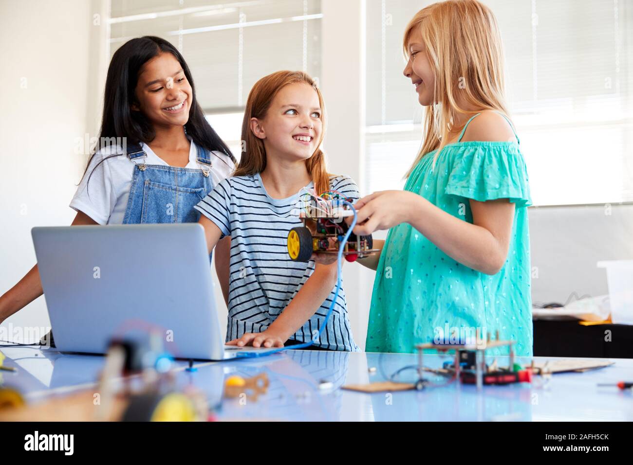 Three Female Students Building And Programing Robot Vehicle In After School Computer Coding Class Stock Photo