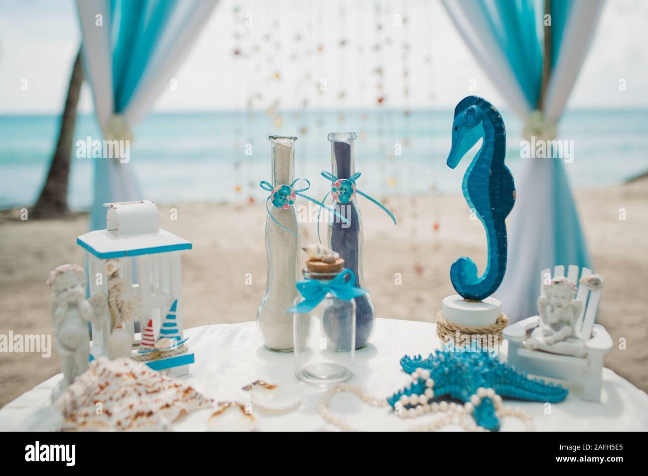 White and blue wedding decorations on a white table on a beach