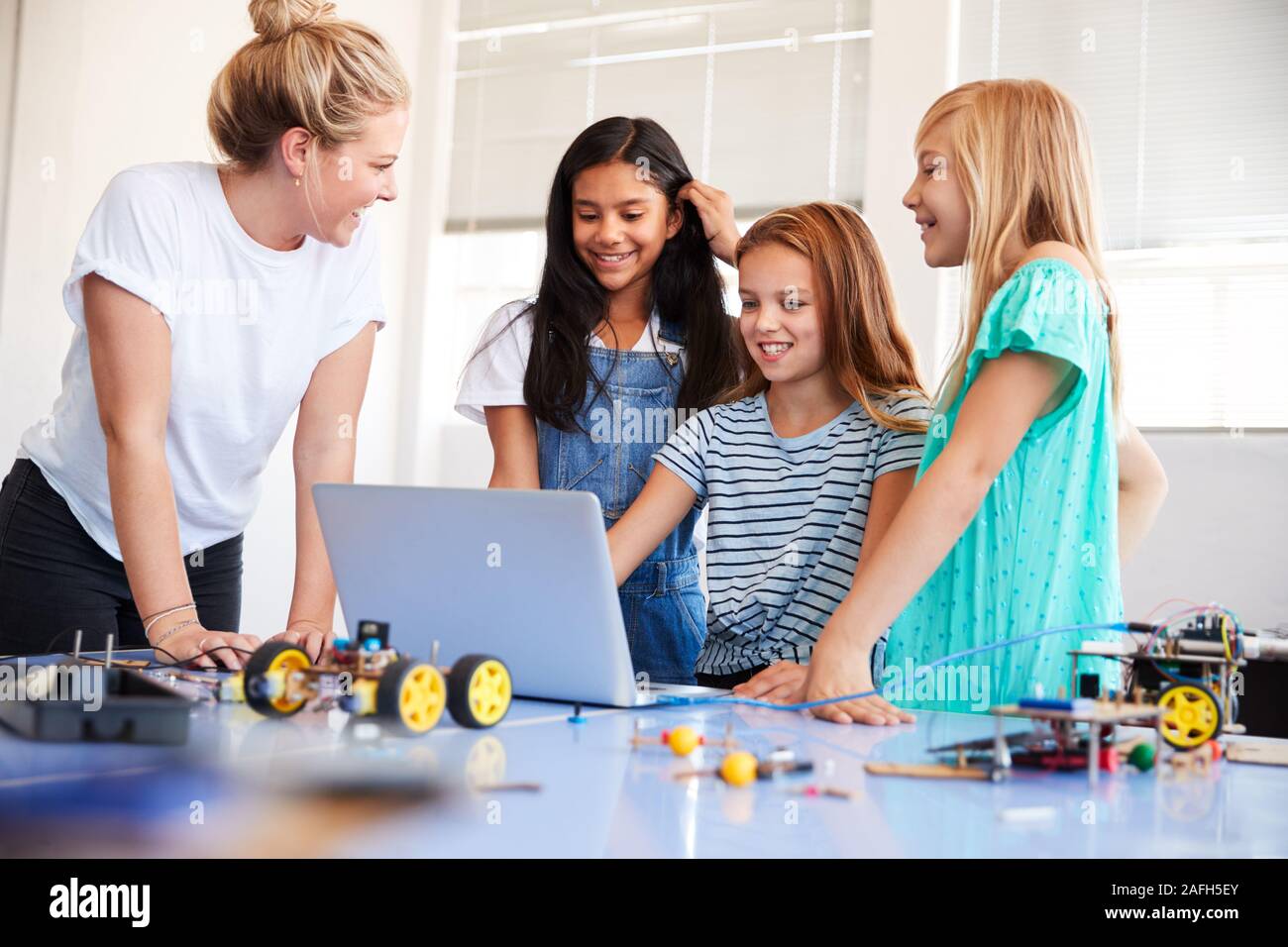 Three Female Students With Teacher Building Robot Vehicle In After ...