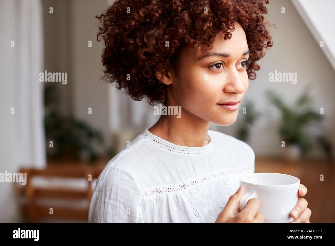 Young Woman Relaxing In Loft Apartment With Hot Drink Stock Photo - Alamy