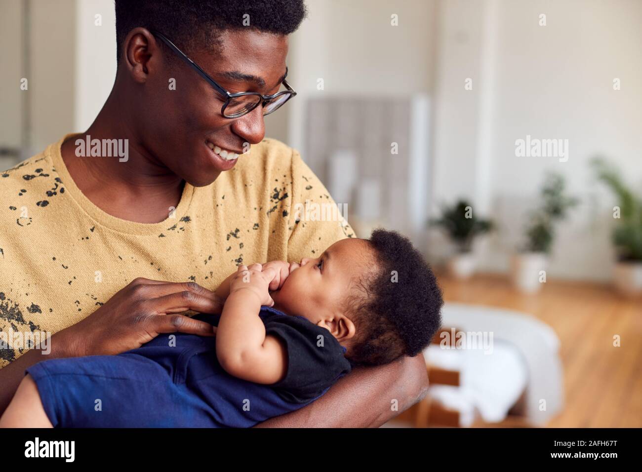 Loving Father Holding Newborn Baby At Home In Loft Apartment Stock Photo