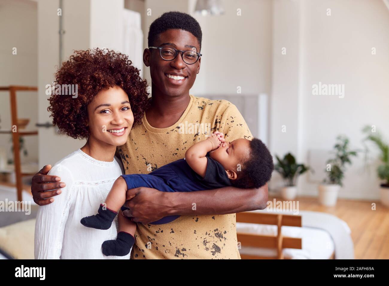 Portrait Of Loving Parents Holding Newborn Baby At Home In Loft Apartment Stock Photo