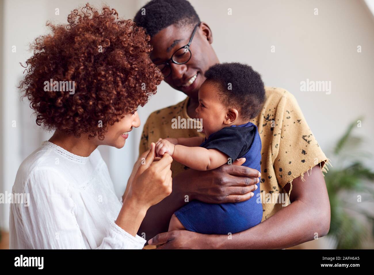 Loving Parents Playing With Newborn Baby At Home In Loft Apartment Stock Photo