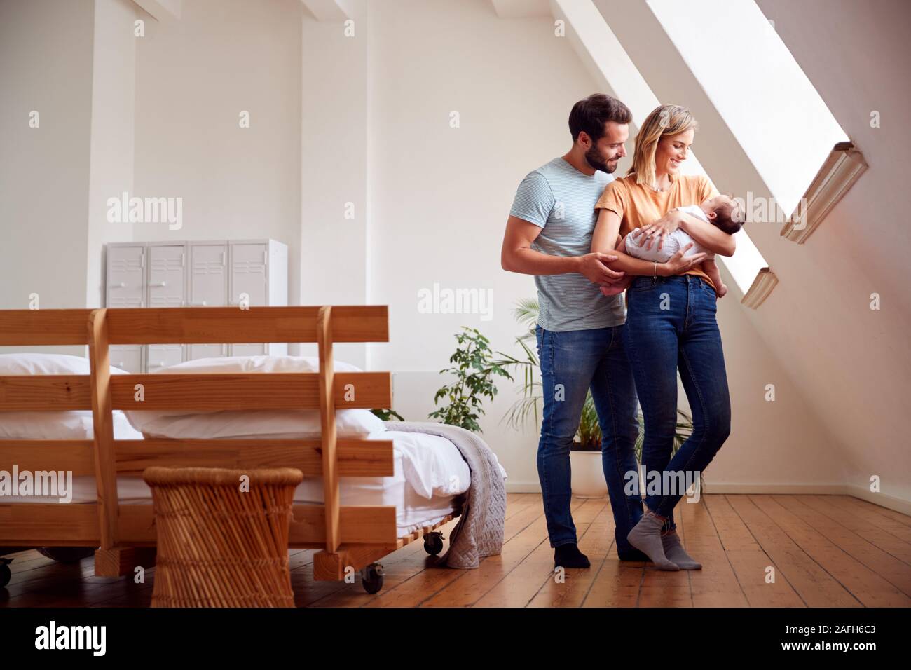 Loving Parents Holding Newborn Baby At Home In Loft Apartment Stock Photo