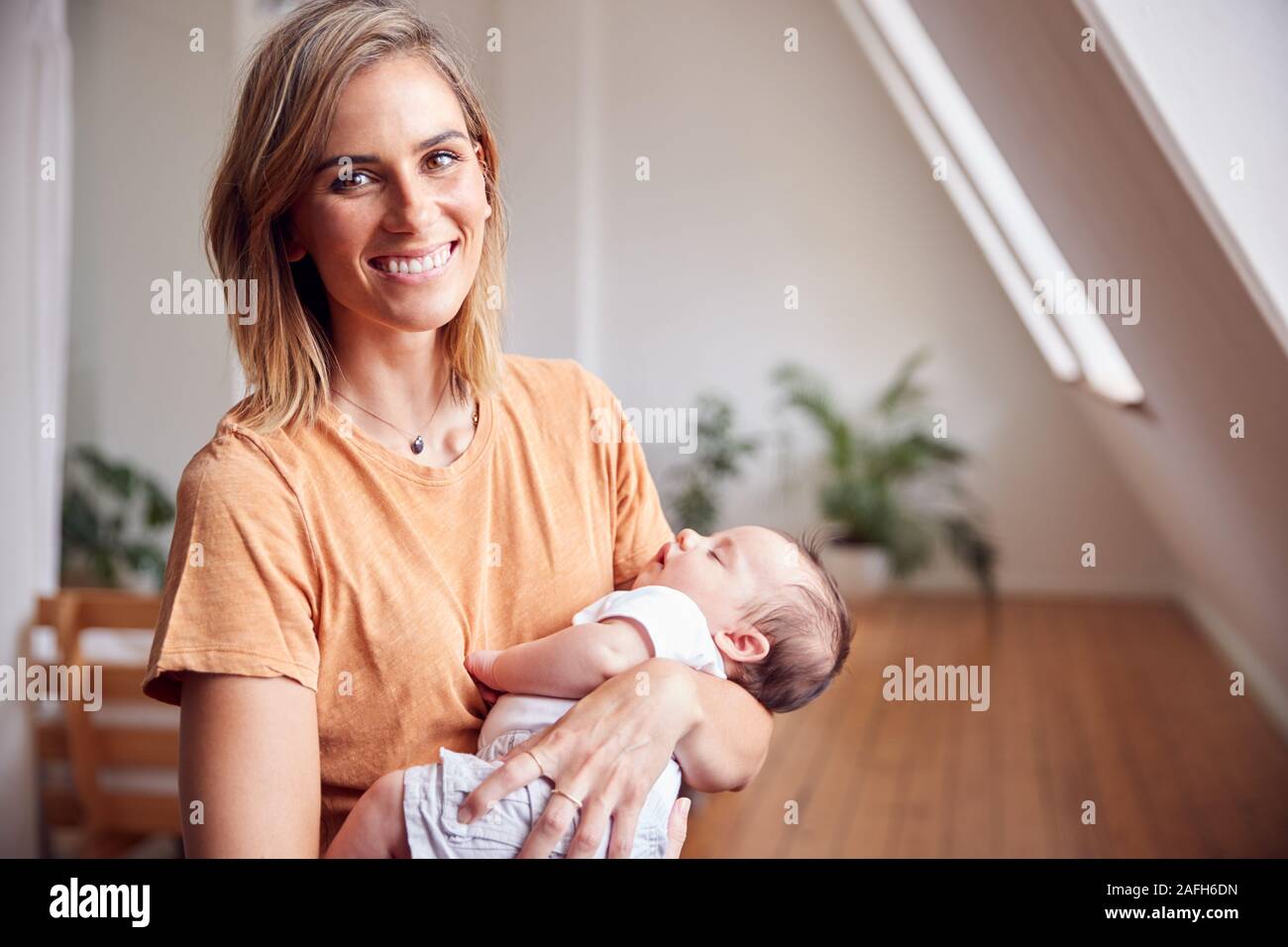 Portrait Of Loving Mother Holding Newborn Baby At Home In Loft Apartment Stock Photo