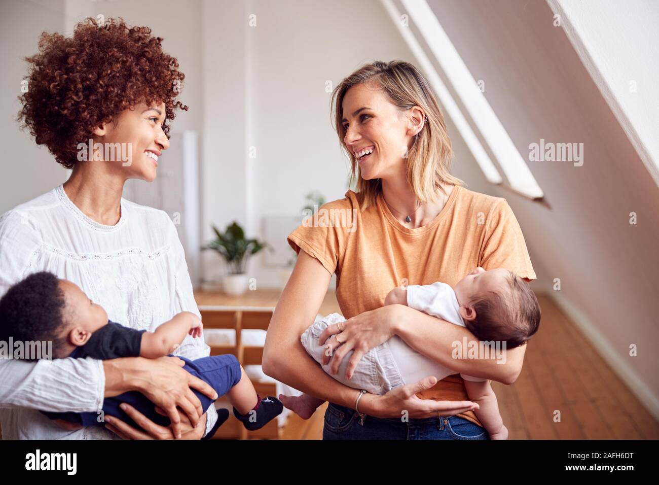 Two Mothers Meeting Holding Newborn Babies At Home In Loft Apartment Stock Photo