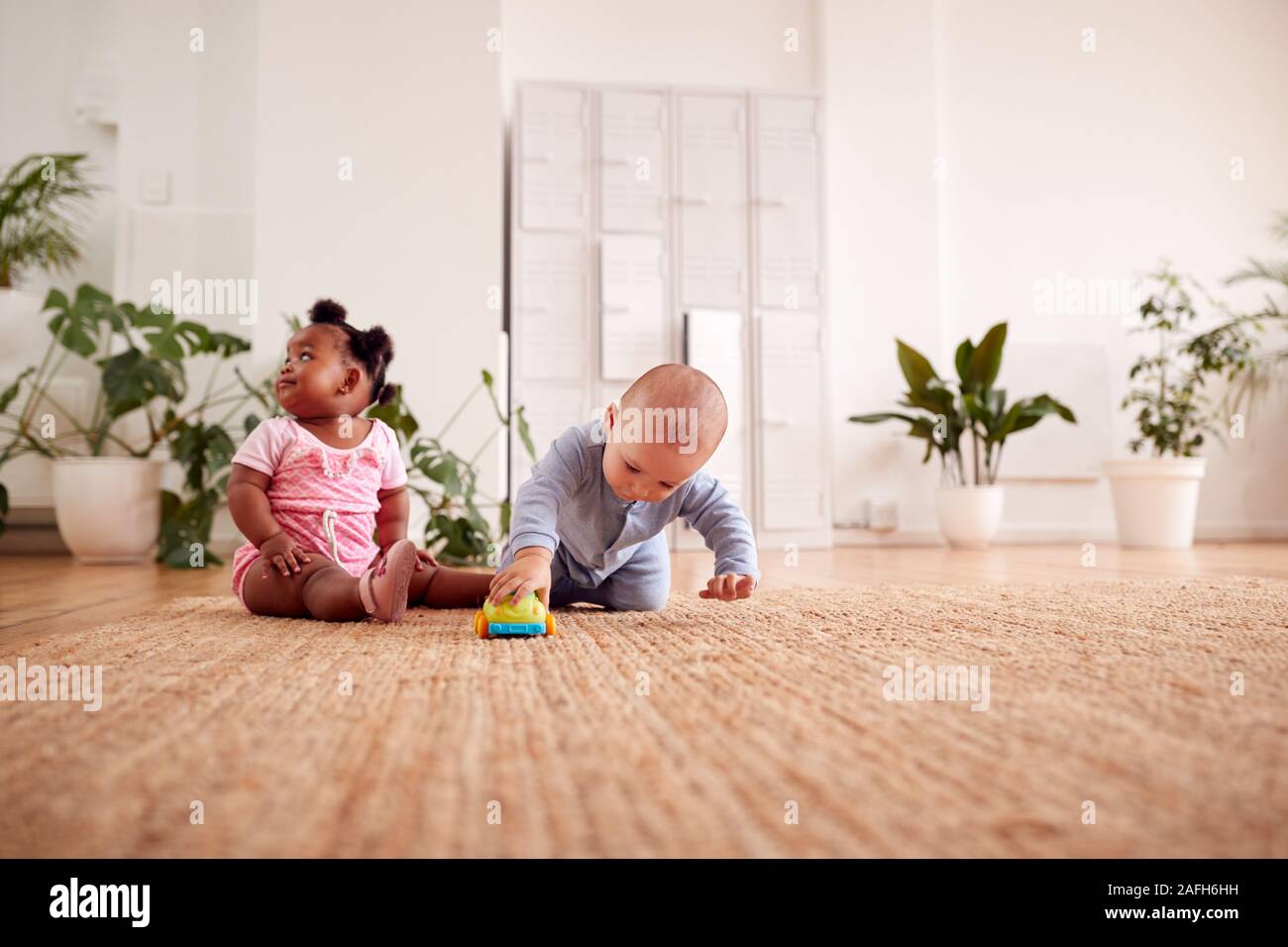 Baby Boy And Girl Playing With Toys On Rug At Home Together Stock Photo