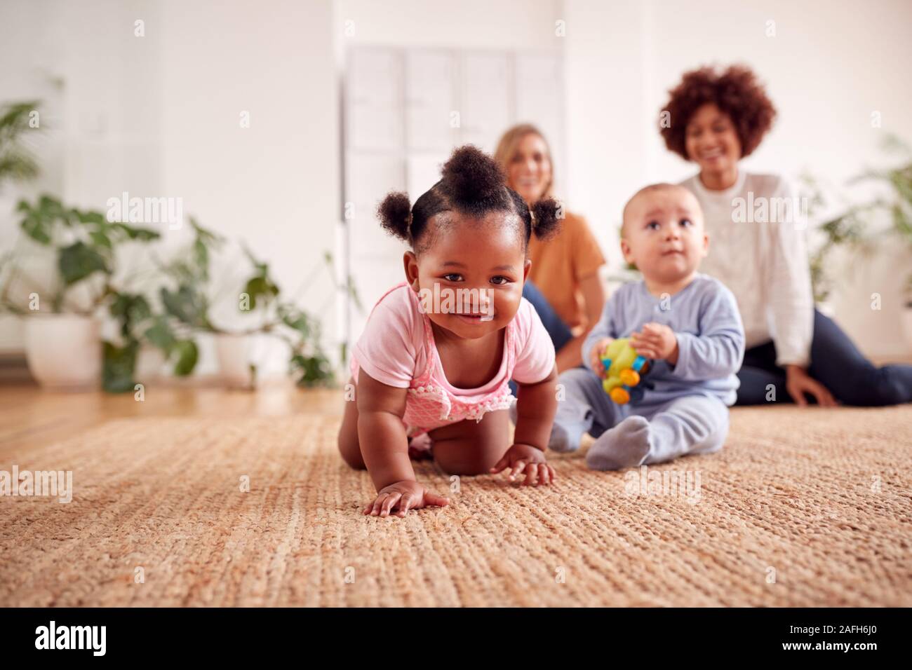 Two Mothers Meeting For Play Date With Babies At Home In Loft Apartment Stock Photo