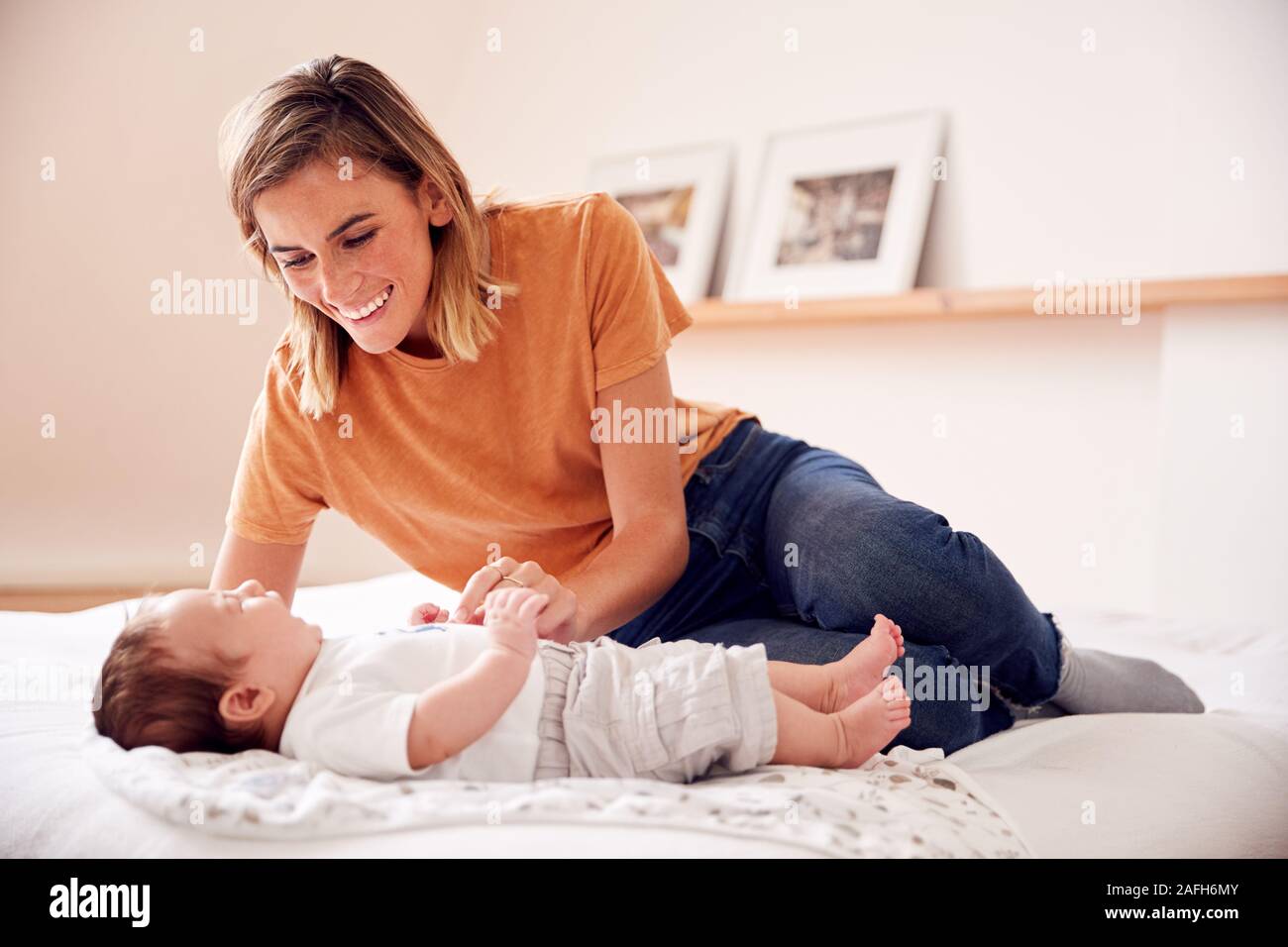 Loving Mother With Newborn Baby Lying On Bed At Home In Loft Apartment Stock Photo