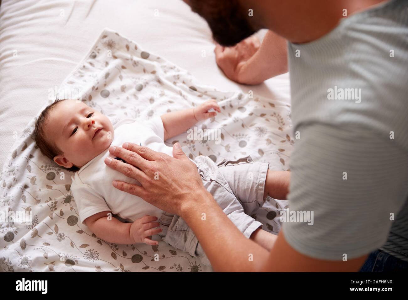 Close Up Of Loving Father Lying With Newborn Baby On Bed At Home In Loft Apartment Stock Photo