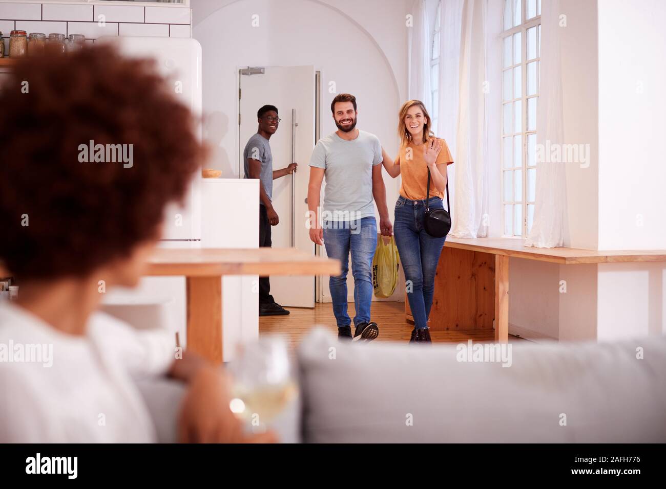 Couple Greeting Friends Arriving For Dinner Party At Home Stock Photo