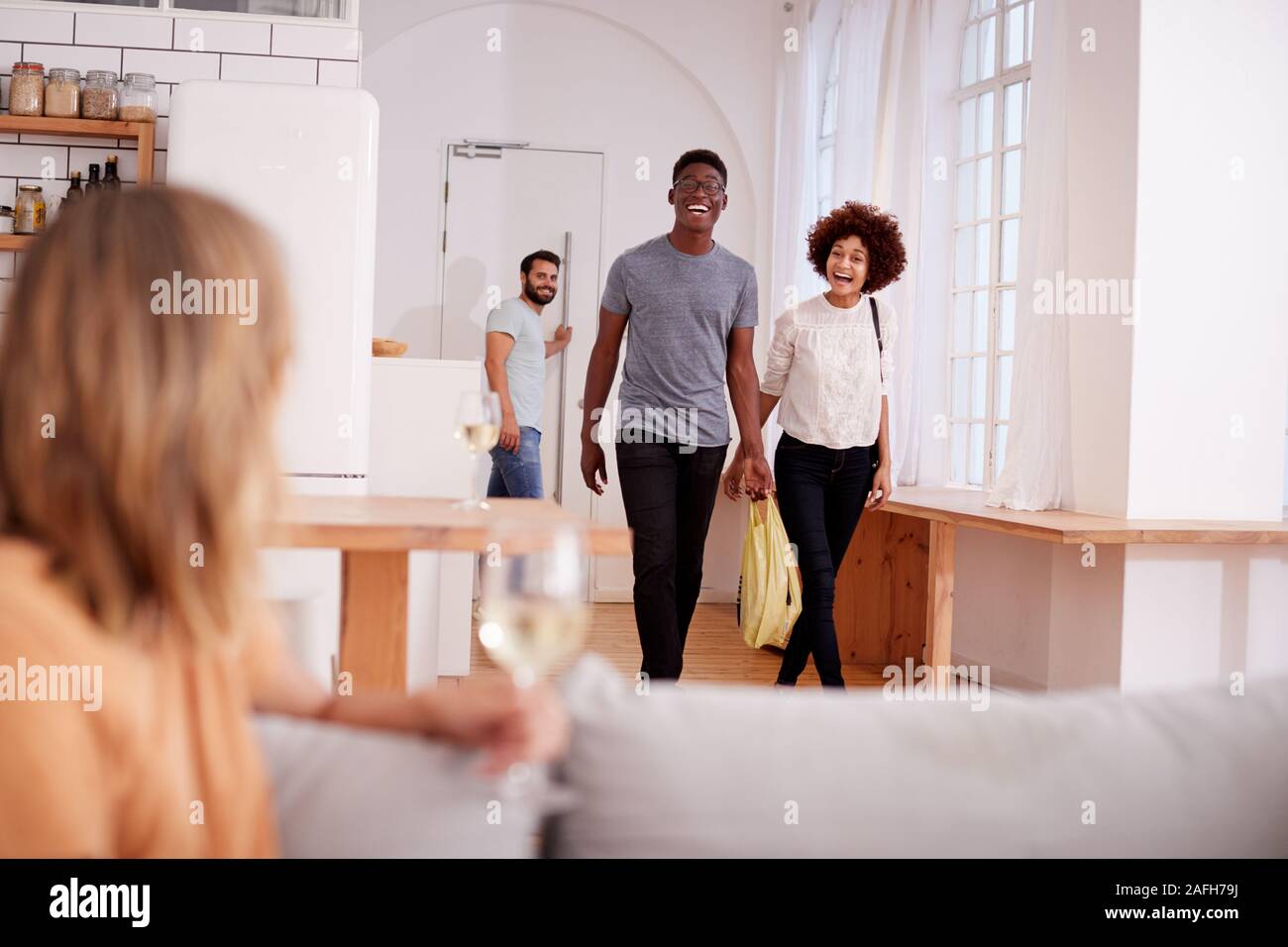 Couple Greeting Friends Arriving For Dinner Party At Home Stock Photo