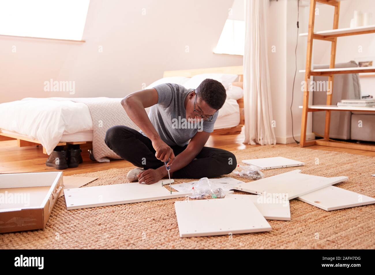 Man In New Home Putting Together Self Assembly Furniture Stock Photo