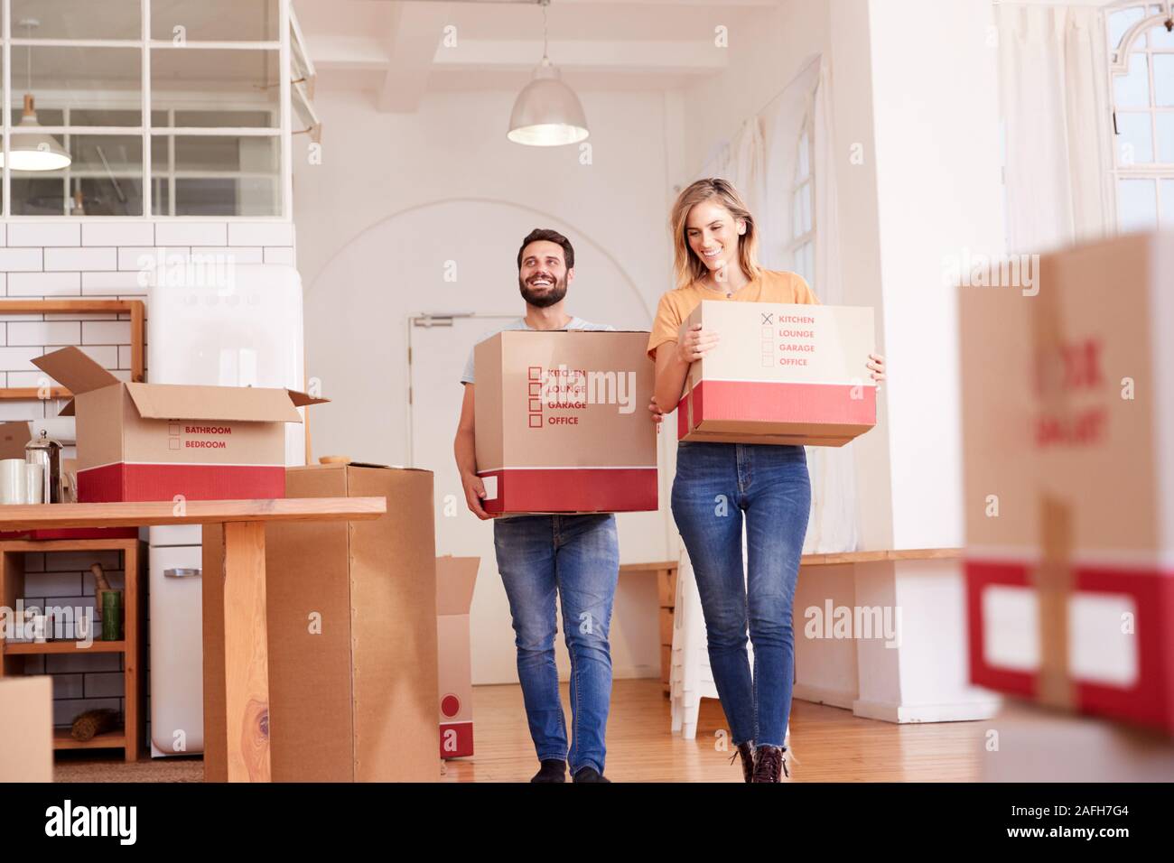 Smiling Couple Carrying Boxes Into New Home On Moving Day Stock Photo