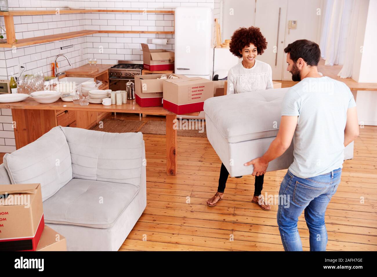 Smiling Couple Carrying Furniture Into New Home On Moving Day Stock Photo