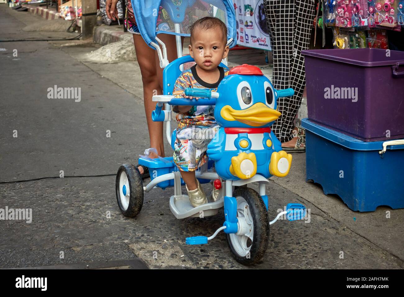 Child riding a cartoon pedal  bike with stabilizers attached. Stock Photo