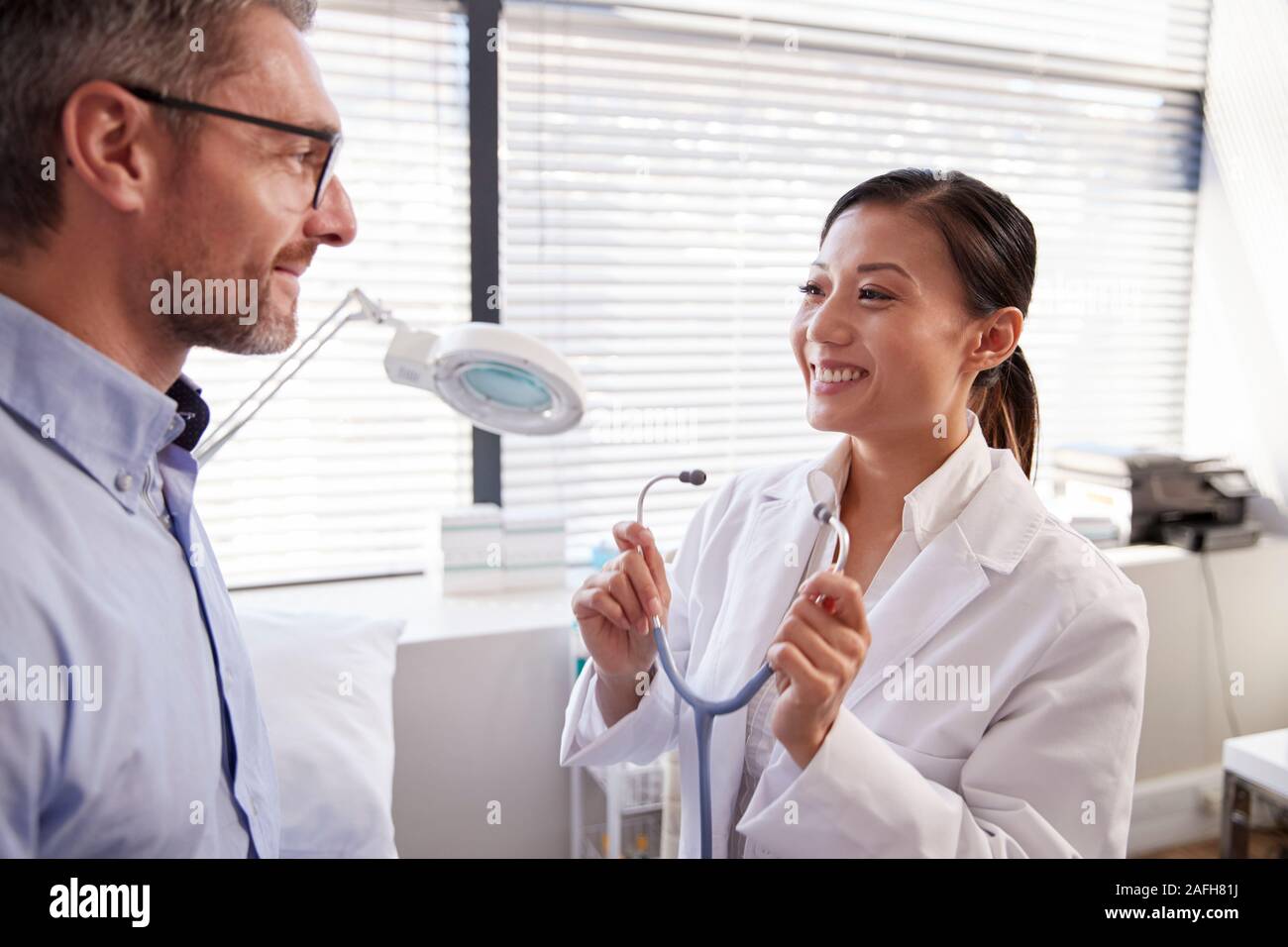 Mature Male Patient Having Medical Exam With Woman Doctor In Office Stock Photo