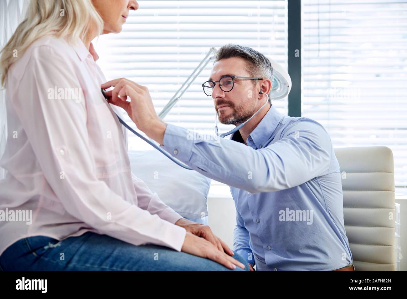 Mature Female Patient Having Medical Exam With Doctor In Office Stock Photo
