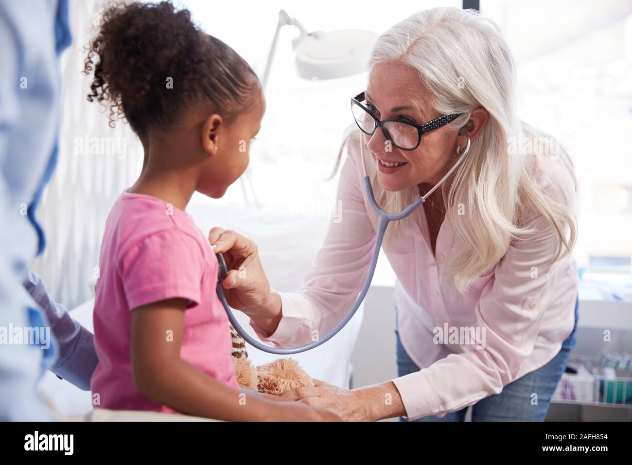 Father With Daughter In Consultation With Doctor In Office Stock Photo